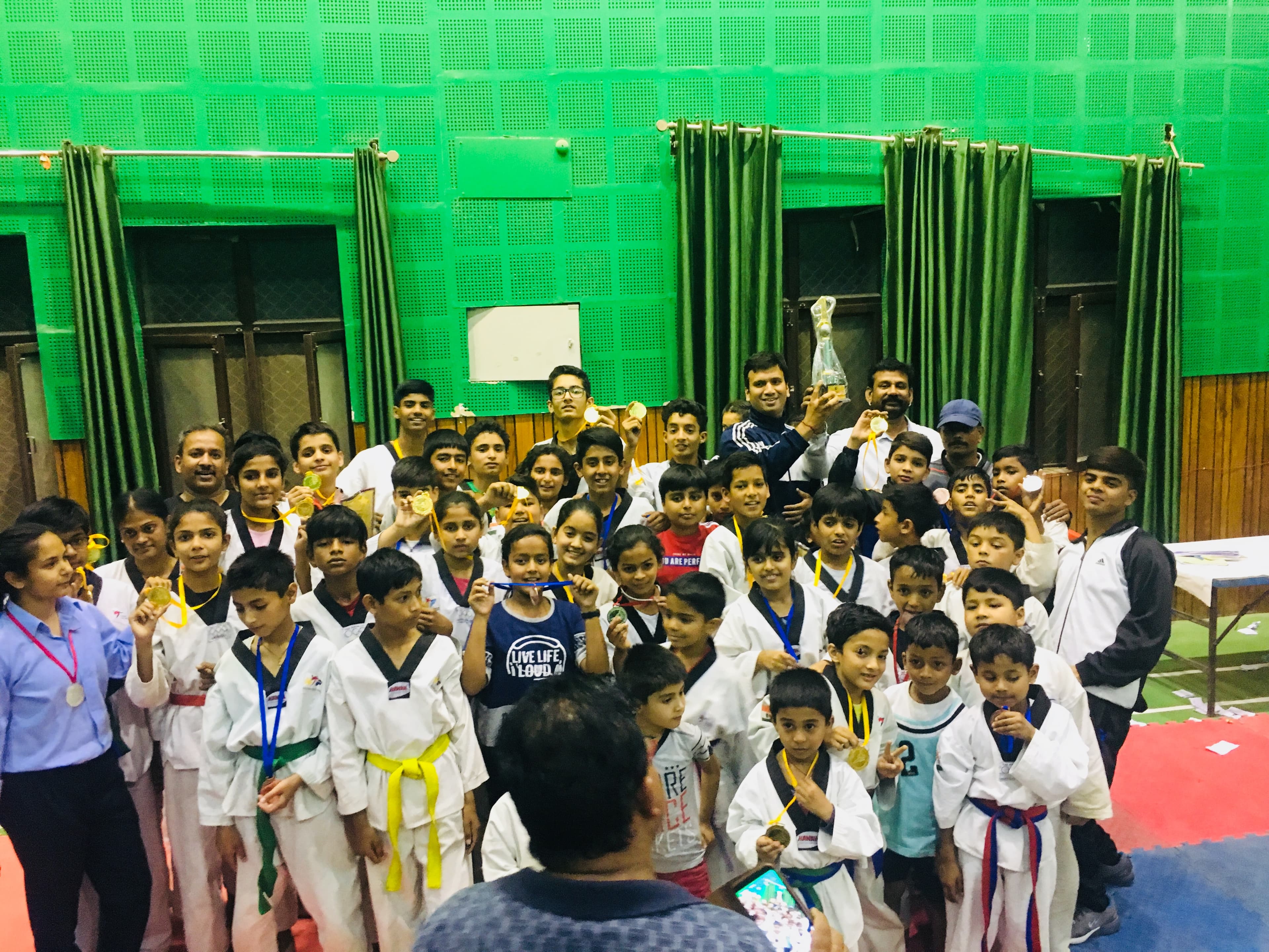 Master Abhishek and the academy's medalists holding up their gold medals and trophy.